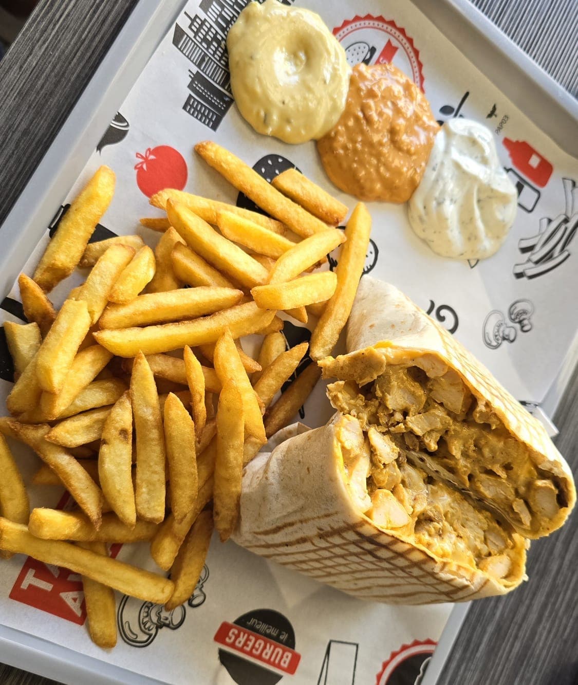Tacos au poulet coupé en deux, servi avec des frites et des sauces